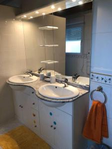 uma casa de banho com 2 lavatórios e um espelho grande em Gîte des Contes em Madiran
