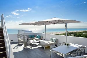 a patio with a table and an umbrella and the beach at Hotel Victor South Beach in Miami Beach