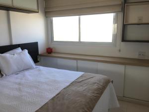 Apartamento Bora Bora Resort في ريو دي جانيرو: غرفة نوم بسرير ابيض ونافذة