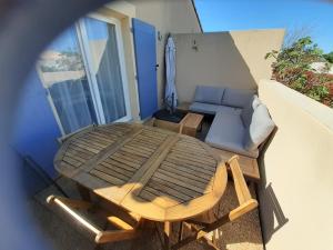 a patio table and a couch on a balcony at Sous le soleil des Alpilles in Mouriès