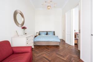 a white bedroom with a bed and a red couch at Breathless view Parliament 2 Luxury Suites with terrace FREE PARKING RESERVATION NEEDED in Budapest