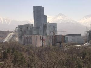 uma cidade com edifícios altos em frente a montanhas nevadas em 2room apartment 100sq m With a Beautiful Mountain views em Almaty