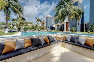 a couch with pillows sitting in front of a swimming pool at Contemporary poolside Condo, Wi-Fi - Paraiso Kaanal 101 in Tulum