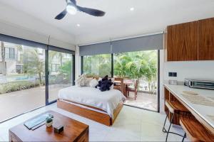 a person sitting on a bed in a room with large windows at Contemporary poolside Condo, Wi-Fi - Paraiso Kaanal 101 in Tulum +19 photos