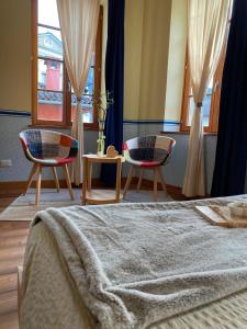 1 Schlafzimmer mit 2 Stühlen und 1 Bett mit einer Decke in der Unterkunft Residenza d'Epoca Albergo Grimani in Ampezzo
