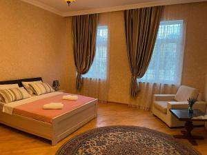 een slaapkamer met een bed, een stoel en ramen bij Sisi Guest House in Koetaisi