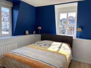 Schlafzimmer mit einem Bett mit blauen Wänden und Fenstern in der Unterkunft Val-André vue sur mer in Pléneuf-Val-André