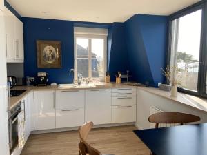 eine Küche mit weißen Schränken und blauen Wänden in der Unterkunft Val-André vue sur mer in Pléneuf-Val-André