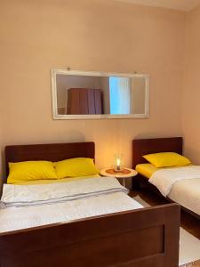 2 bedden met gele kussens in een kamer met een spiegel bij S&I room in Kotor