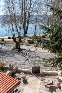 a patio with tables and trees next to the water at Αρχοντικό Κίτσου - BOUTIQUE HOTEL in Kastoria
