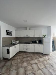 a kitchen with white cabinets and a tile floor at San Agustin apartments , close to the BEACH, with pool! in San Bartolomé