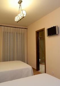 - une chambre avec un lit et une télévision à écran plat dans l'établissement Hostal Rural El Tejar, à Layos