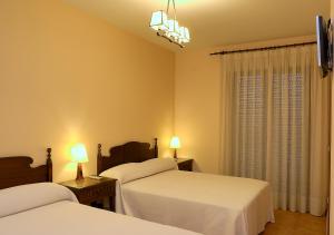 a bedroom with two beds and two lamps and a window at Hostal Rural El Tejar in Layos