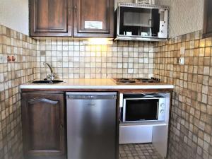 eine kleine Küche mit einer Spüle und einer Mikrowelle in der Unterkunft Appartement Auris, 2 pièces, 4 personnes - FR-1-297-133 in Auris