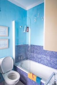 La salle de bains est pourvue de carrelage bleu, de toilettes et d'une baignoire. dans l'établissement Mar y Sol, à Los Cancajos