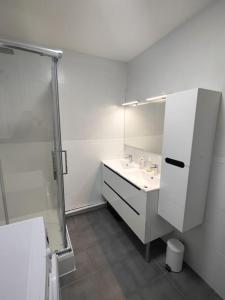 een witte badkamer met een wastafel en een spiegel bij Spacieux 4 chambres au cœur de Cergy in Cergy