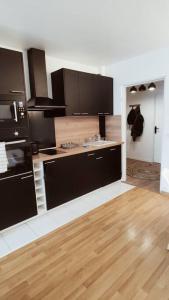 een keuken met zwarte apparatuur en een houten vloer bij Spacieux 4 chambres au cœur de Cergy in Cergy
