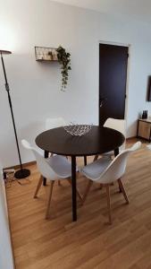 een eetkamer met een tafel en twee witte stoelen bij Spacieux 4 chambres au cœur de Cergy in Cergy