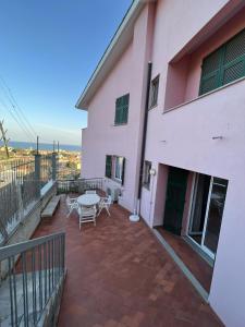a balcony of a pink house with a table and chairs at Appartamento vista mare in villa in Spotorno