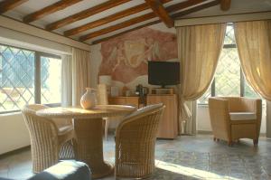 Hotel Villa Clementina في براتشيانو: غرفة طعام مع طاولة وكراسي وتلفزيون