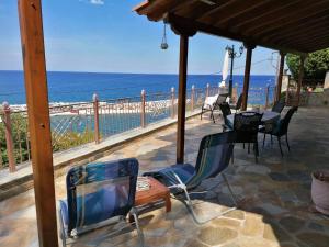 a patio with a tv and chairs and the ocean at The StoneHouse in Keramídhion
