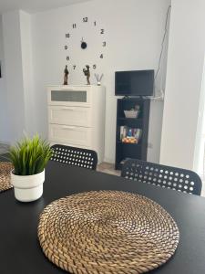 a black table with chairs and a clock on the wall at San Agustin2, quiet apartment close to the beach in San Bartolomé de Tirajana