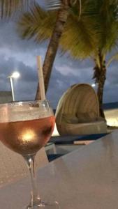 a glass of wine sitting on a table next to a beach at DREAM ON THE BEACH in Baie Nettle