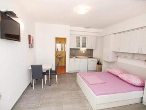 um quarto com uma cama rosa e uma cozinha em Apartman Nikolić 1 em Makarska