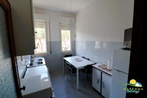 una pequeña cocina blanca con mesa y fregadero en Maremma Holidays : Trasimeno Apartment, en Follonica