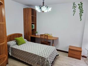 um quarto com uma cama, uma mesa e um lustre em Ático en primera línea de playa em Ribeira