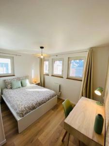 a bedroom with a bed and a table and windows at Les Deux Anges in Rouen
