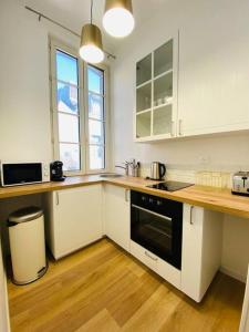 a kitchen with white cabinets and a black oven at Les Deux Anges in Rouen