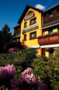 un edificio amarillo con flores delante en Pension Schanzenblick, en Kurort Oberwiesenthal