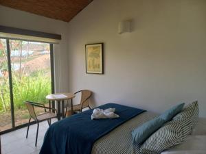 Schlafzimmer mit einem Bett, einem Tisch und einem Fenster in der Unterkunft Hotel Suamena in Ráquira