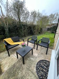 a patio with three chairs and a table with a yellow blanket at One Bed Apartment Stevenage in Stevenage