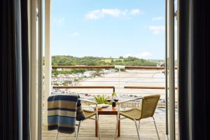 a balcony with a table and chairs and a view of a harbor at St Brides Spa Hotel & Village Apartments in Saundersfoot