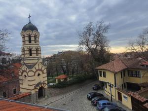 una iglesia con una torre con coches estacionados frente a ella en HANCHO - OLD CITY PLOVDIV Center en Plovdiv
