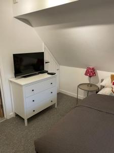 a bedroom with a bed and a tv on a dresser at Little Moat - Moat Farm Barns a small modern studio in the garden on our family farm in Evesham