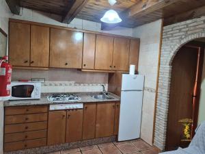 cocina con armarios de madera y nevera blanca en Casas Rurales Los Enebros Nerpio en Nerpio