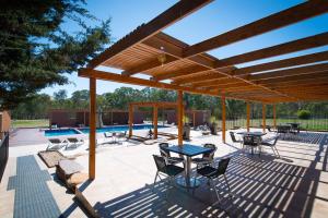 Un patio con mesas y sillas bajo una pérgola de madera. en Mansfield Country Resort, en Mansfield
