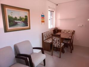 a dining room with a table and chairs and a painting at Recanto de Flor in Mucugê
