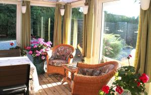 a screened in porch with chairs and a table and flowers at Hine Bakke Bed And Breakfast in Rudkøbing