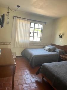 1 dormitorio con 2 camas y ventana en Hotel Real de Huasca, en Huasca de Ocampo