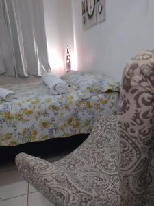 a bed with a blanket and a chair in a room at APARTAMENTO NA DIVISA DE BRASÍLIA AO LADO SHOPING SUL VALPARAÍSO GO. in Valparaíso de Goiás