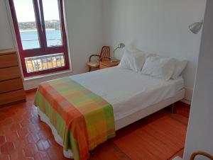 a bedroom with a bed with a colorful blanket and a window at Flat Vista RioMar by Francisco in Portimão