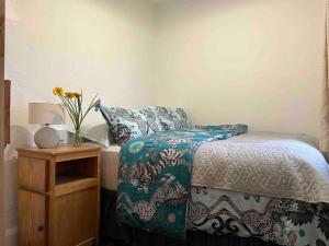 Un dormitorio con una cama y una mesa con un jarrón de flores en Blue Cottage en Valentia Island