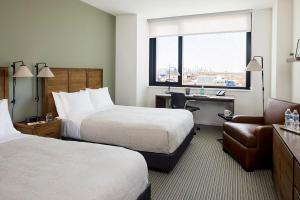 a hotel room with two beds and a chair at The Study at the University of Chicago in Chicago