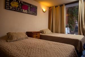 two beds in a hotel room with a window at Hostal Casa de Huéspedes 269 in Santiago