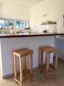 una cocina con 2 taburetes de madera frente a un mostrador en CasaNorte Hospedaje en Miraflores, Catamarca 