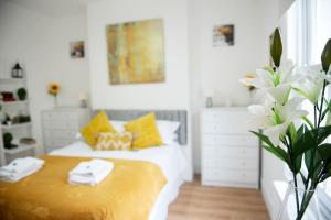 a bedroom with a bed with yellow and white pillows at King's Central Cambridge Apartment in Cambridge